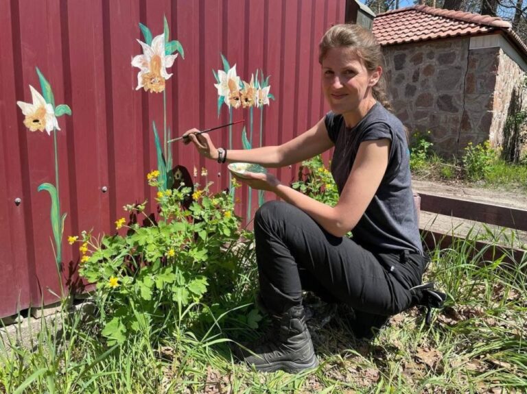 À Bucha, en Ukraine, une femme peint des fleurs autour des impacts de balles